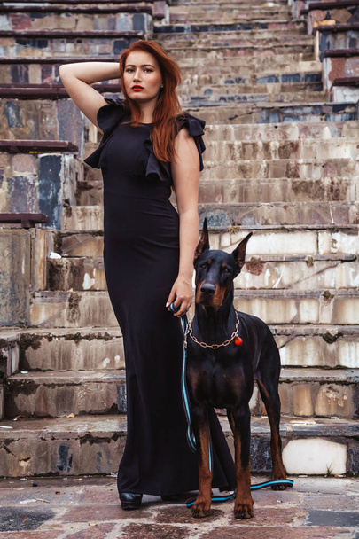 beautiful woman owner with her dog black doberman outdoor walking together - Foto, Bild