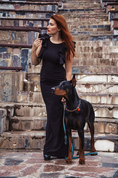 όμορφη γυναίκα ιδιοκτήτη με το σκύλο της μαύρο Ντόμπερμαν υπαίθρια Περπάτημα μαζί - Φωτογραφία, εικόνα