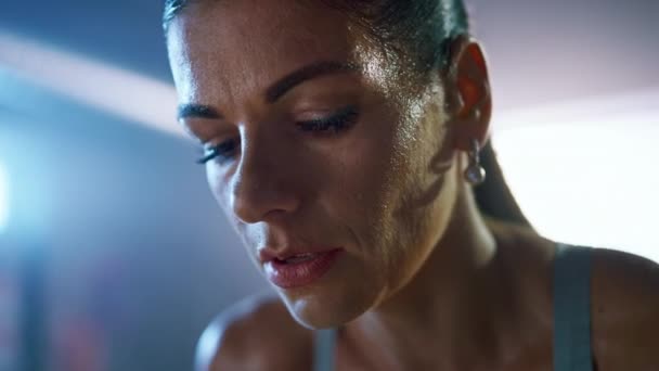 Close Up Portrait of a Beautiful Strong Fit Brunette Wiping Sweat from Her Face in a Loft Industrial Gym with Motivational Posters. She's Catching Her Breath after Intense Fitness Training Workout. - Footage, Video