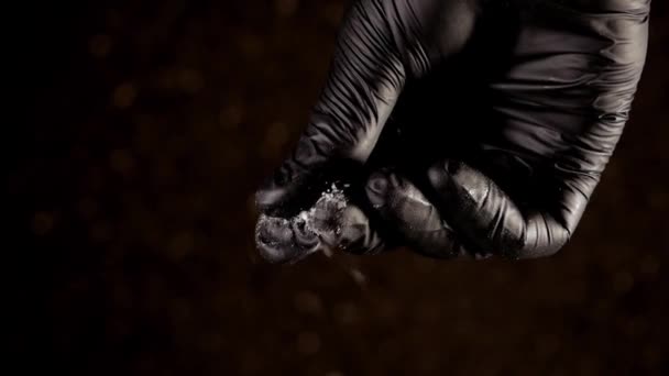 Hand in black glove sprinkles salt down in slow motion. - Filmati, video