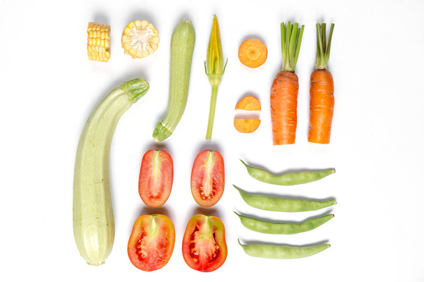 Creative layout made of haricot, tomatoes, corn, carrot, zucchinion white background . Flat lay, top view, copy space. Healthy eating concept. - Photo, image