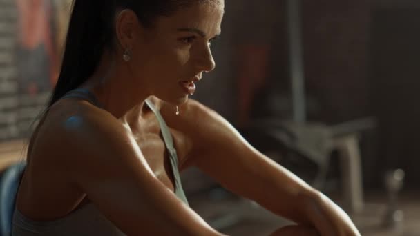 Beautiful Strong Fit Brunette in Sport Top and Shorts in a Loft Industrial Gym with Motivational Posters. She's Catching Her Breath after Intense Fitness Training Workout. Sweat All Over Her Face. - Video, Çekim