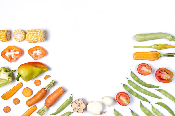 Creative layout made of haricot, tomatoes, pepper, carrot, garlic, maize, zucchini and onion. Organic food background. Flat lay, top view, copy space. Healthy eating concept. - Photo, Image