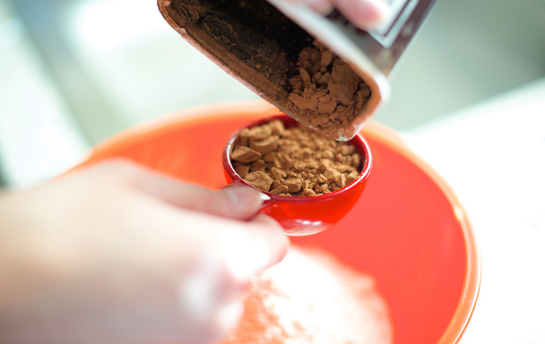Despejar pó de chocolate em copo de medição
 - Foto, Imagem
