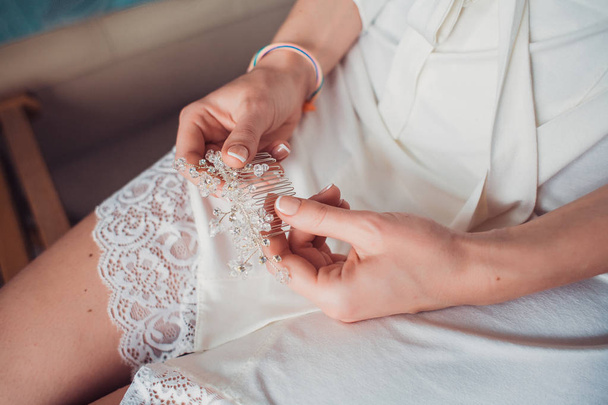Close-up image of bridal hair clip in hands of bride. - Fotografie, Obrázek