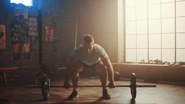 Handsome Muscular Man Does Overhead Deadlift with a Barbell in a Small Authentic Gym. Athletic Man Training His Arm Muscles and Exercises with Barbell. Workout in the Hardcore Gym. Warm Light. - Filmagem, Vídeo