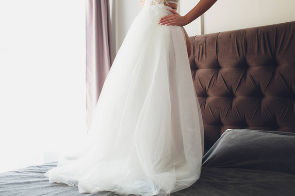 Closeup toned photo of beautiful bride tying up her wedding dress. - Zdjęcie, obraz