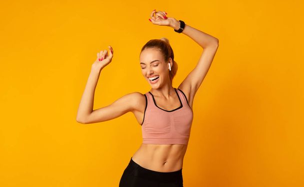 Excited Young Lady In Sportswear Dancing On Yellow Background - Фото, изображение