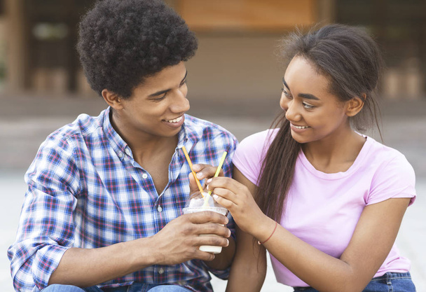 Teini-ikäiset juovat pirtelöä ulkona flirttailemassa keskenään
 - Valokuva, kuva