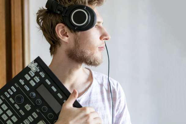 MIDI kontrolör ve kulaklık f tutan genç sakallı adam ses yapımcısı portresi - Fotoğraf, Görsel
