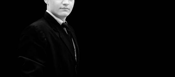 Portrait d'un homme d'affaires vêtu d'une veste de couleur bleu foncé et d'une cravate noire isolée sur le noir et présentant un succès avec les mains pliées.
. - Photo, image