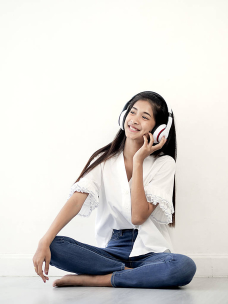 Asian teenager girl using headphone while sitting on the floor a - Fotó, kép