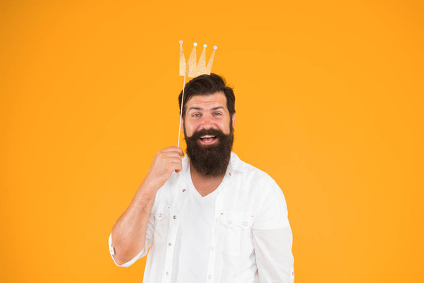Handsome bearded guy king. King of party. Costume party. Holiday carnival celebration. Birthday boy. Guy in yellow background posing with booth props. Photo booth fun. Bearded man king costume party - Foto, Bild