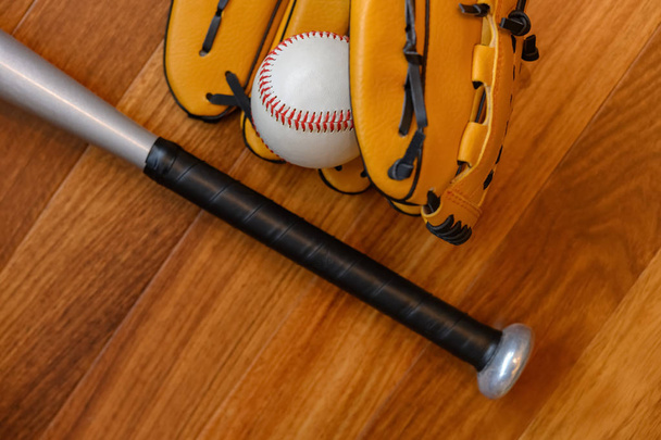 Baseballschläger und Ball und Handschuh auf dem Boden eines Wohnzimmers - Foto, Bild
