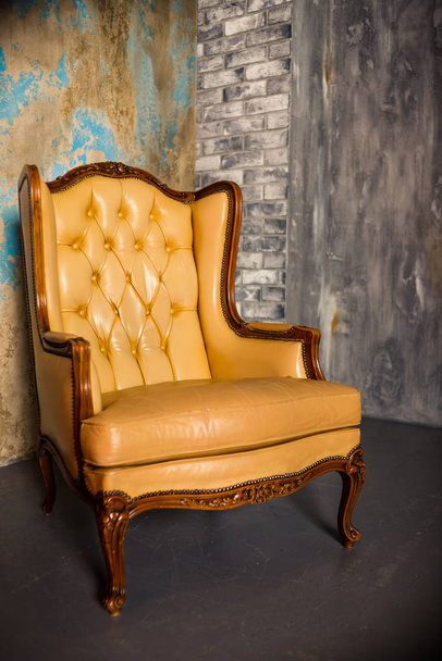 Luxe houten stoel met beige leer. Antieke fauteuil geïsoleerd op concrete achtergrond. elegant design. klassieke Royal luxe stijl. mooie bruine fauteuil in appartement - Foto, afbeelding