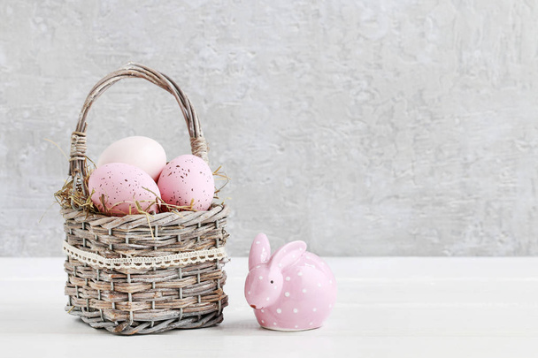 Wicker basket with Easter eggs and ceramic rabbit figure - 写真・画像