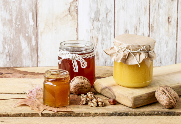 Honey in glass jar on wooden background - Valokuva, kuva