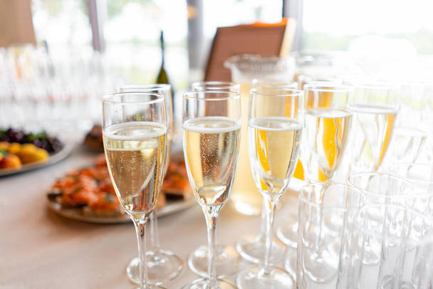 recepción. Mesa llena de copas de vino blanco espumoso con canapés y antipasti en el fondo. burbujas de champán
 - Foto, imagen
