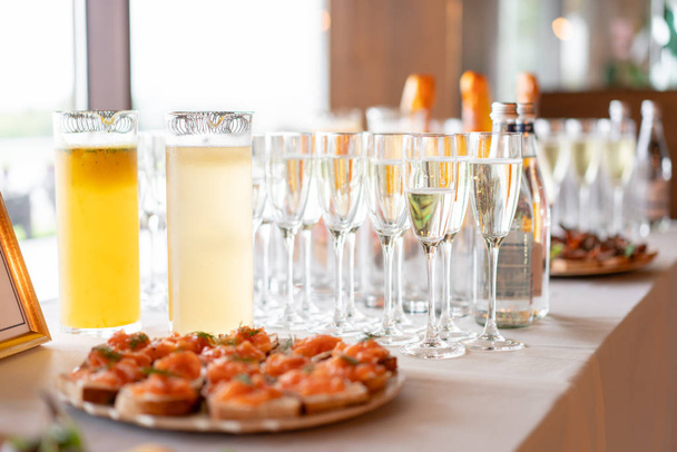 recepción. Mesa llena de copas de vino blanco espumoso con canapés y antipasti en el fondo. burbujas de champán
 - Foto, imagen