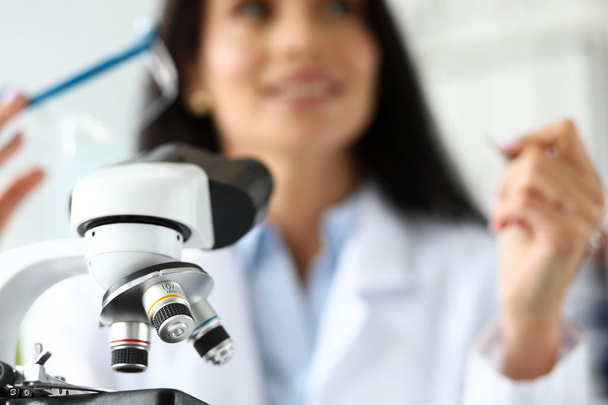 Lente de microscópio científico com analista feminina em segundo plano
 - Foto, Imagem
