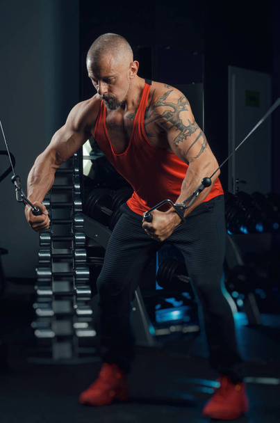 сильний м'язистий чоловік тренується в спортзалі
 - Фото, зображення
