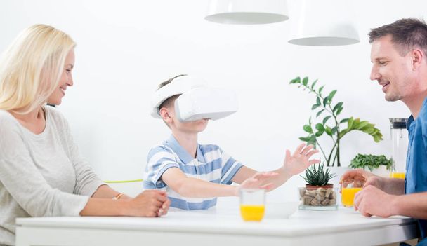 Felice famiglia caucasica a casa a tavola da pranzo, divertirsi giocando con cuffie realtà virtuale
 - Foto, immagini