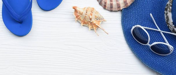 白い木製の背景にサンダルと貝殻と夏の帽子とサングラス - 写真・画像