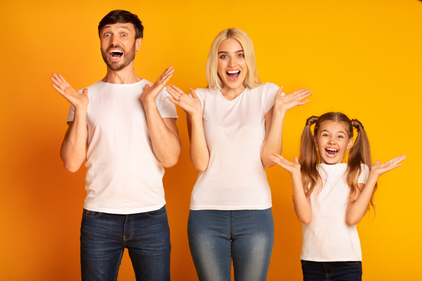 Sorprendidos padres e hija gritando en deleite sobre fondo amarillo
 - Foto, imagen