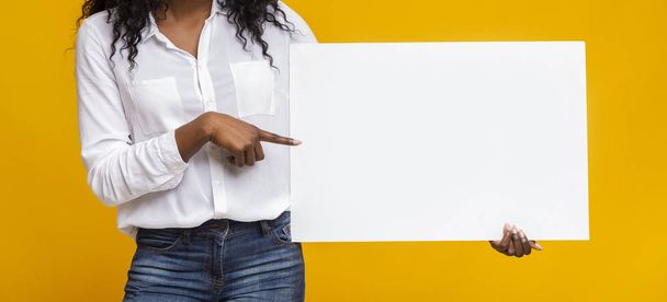 Afro girl is pointing at yellow advertising board - Photo, Image