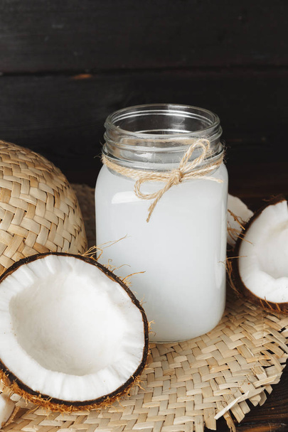 Coconut milk glass jar close up on wooden background - Foto, afbeelding