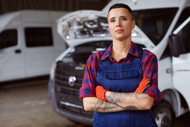 Female auto mechanic in overalls poses at the camera. - Фото, изображение