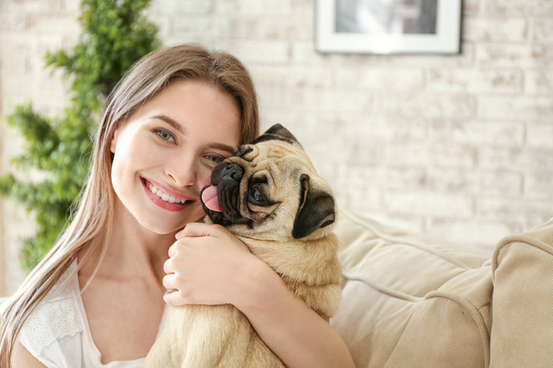 Hermosa mujer joven con lindo perro pug en casa
 - Foto, imagen