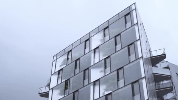 Unterseite des modernen Hauses mit Spiegelfassade. Aktion. moderne Designlösung in Glasfassade eines kleinen Hauses vor grauem Himmel - Filmmaterial, Video