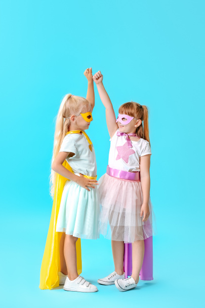 Roztomilá děvčata oblečená jako superhrdinové na barevné pozadí - Fotografie, Obrázek