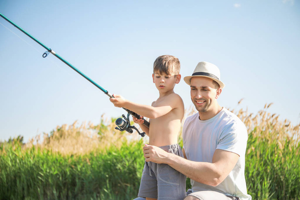 Father and son fishing together on river - Foto, Bild