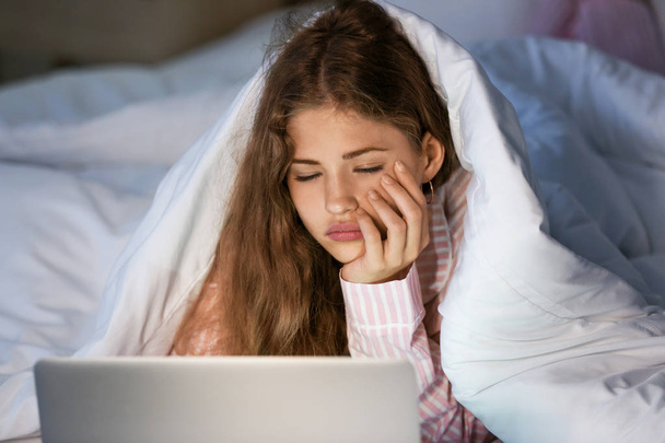 Tired teenage girl with laptop in bed at night - Foto, Imagem
