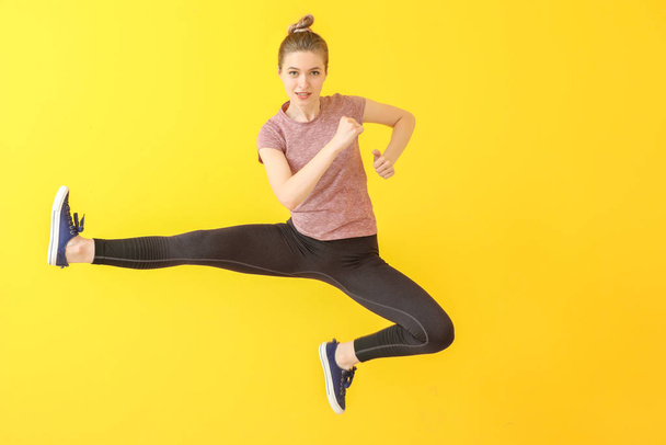 Jumping sporty woman on color background - Valokuva, kuva
