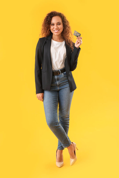 Beautiful African-American woman with credit card on color background - 写真・画像