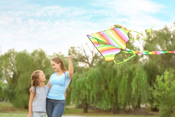 Jeune femme avec petite fille volant cerf-volant en plein air
 - Photo, image