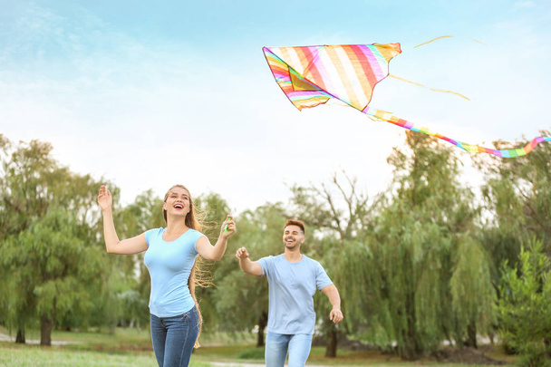 Happy young couple flying kite outdoors - Foto, afbeelding