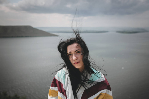 Stylish hipster girl with windy hair sitting on top of rock moun - Foto, imagen
