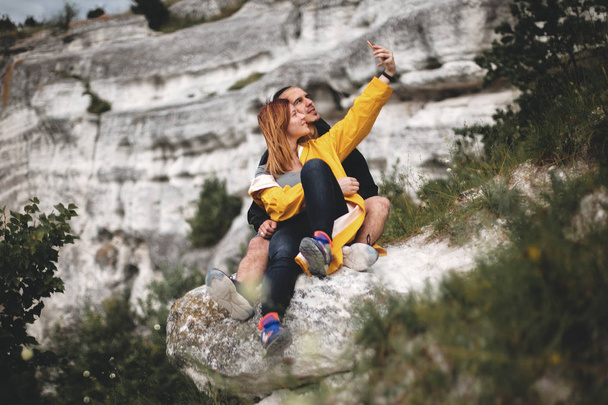 glückliches Hipster-Paar macht Selfie mit dem Handy auf dem Gipfel des Felsens - Foto, Bild