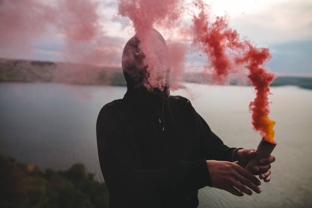 Ultras hooligan holding red smoke bomb in hand, standing on top  - Foto, Imagem