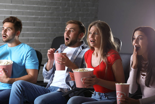 Friends with popcorn watching horror movie in cinema - Foto, afbeelding