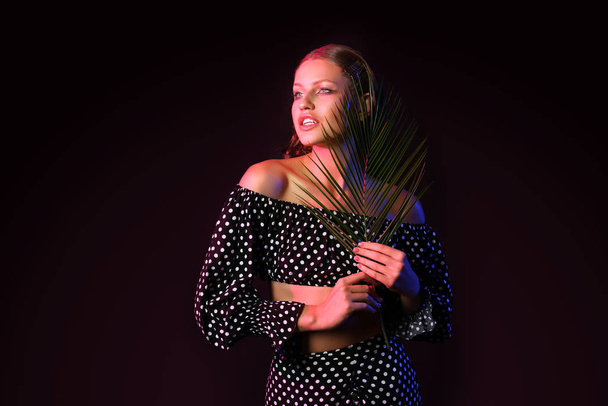 Divatos fiatal nő trópusi leveles sötét háttér - Fotó, kép