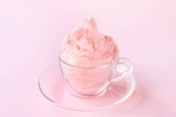 Glass cup with tasty cotton candy on color background - Foto, imagen