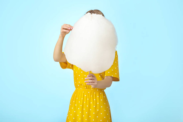 Young woman with tasty cotton candy on color background - 写真・画像