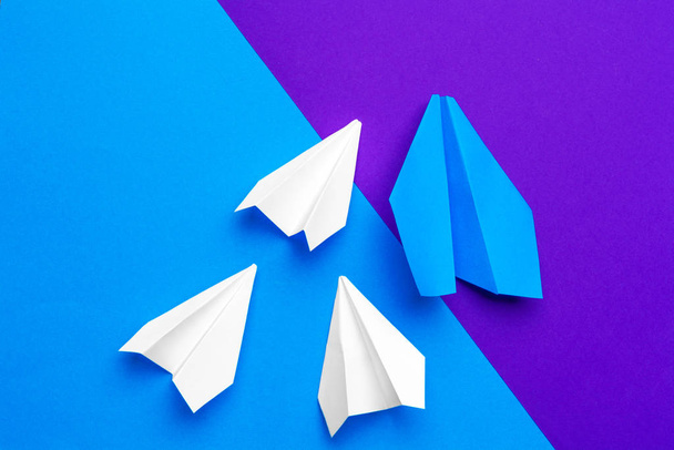 white paper airplane on a blue and purple paper background - Фото, зображення