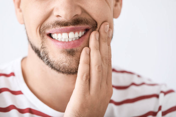 Man suffering from toothache against light background, closeup - Photo, Image