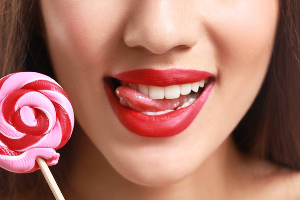 Beautiful young woman with bright lipstick and lollipop, closeup - Fotografie, Obrázek